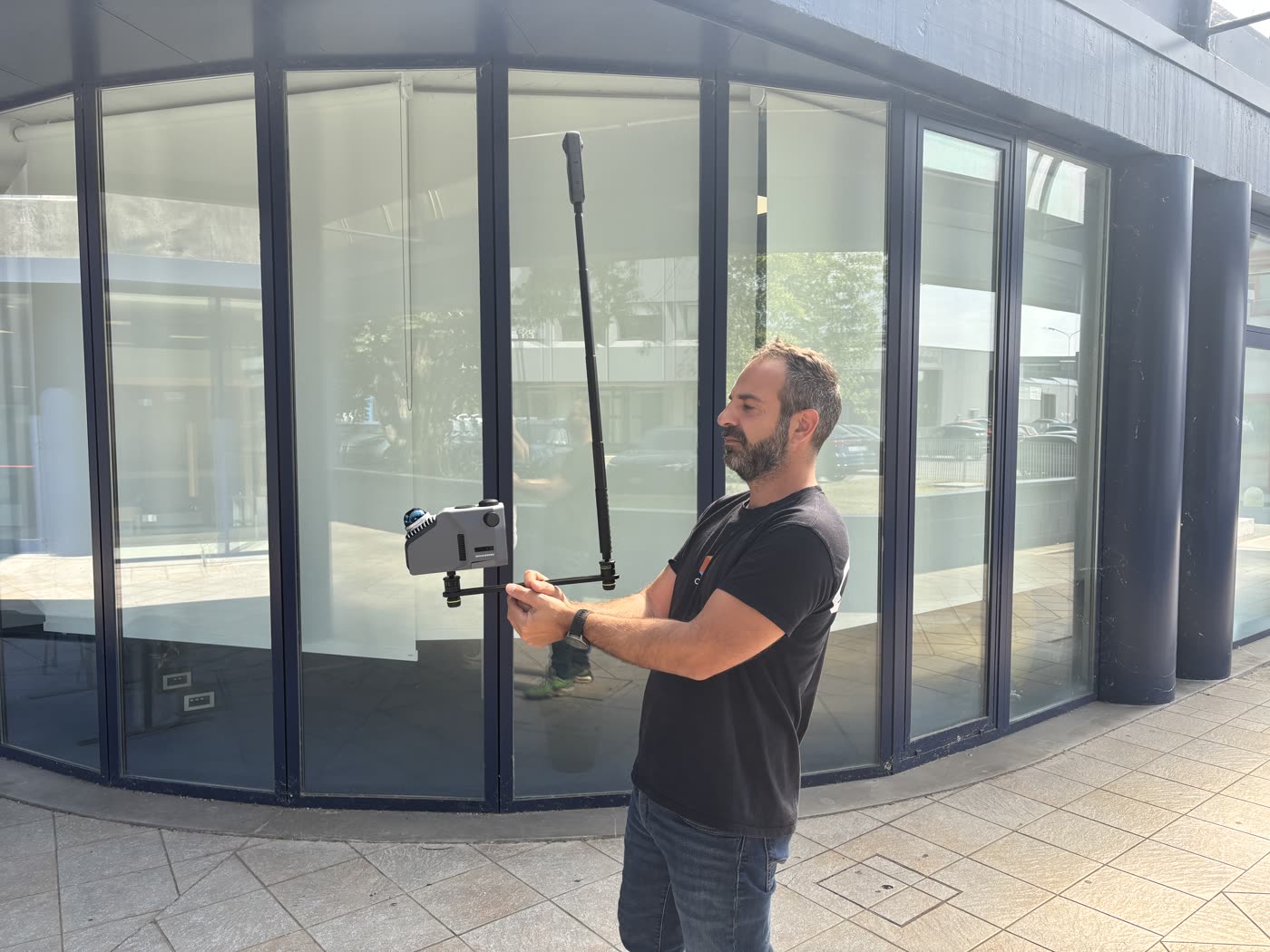 The capture rig in use: dual-fisheye 360-degree camera on top of the pole, Eagle LIDAR scanner mounted on the crossbar roughly 70 cm below